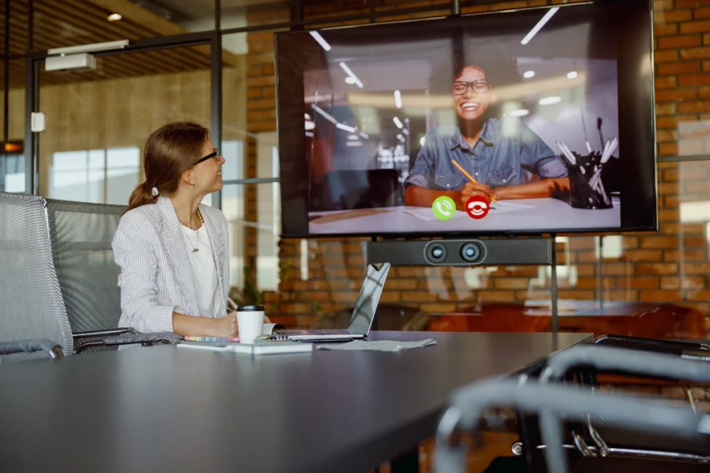Businesswoman using meeting room technology to host a remote videoconference.