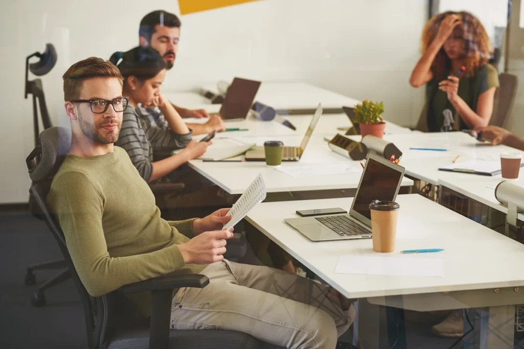 Office worker experiencing distraction while coworkers work in the background