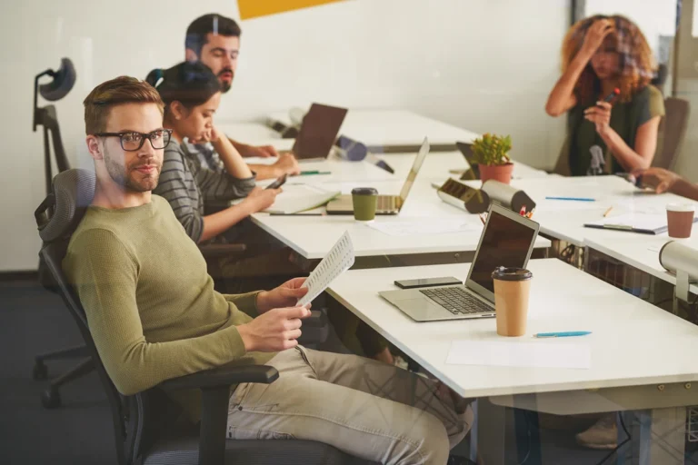 Office worker experiencing distraction while coworkers work in the background