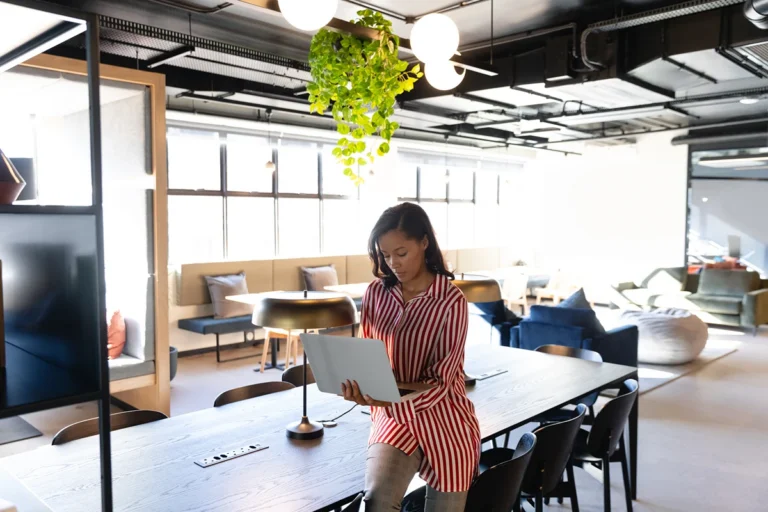 Woman using laptop in front of hot desks in a coworking space